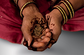 Guar seeds in the palm of a hand, used to extract guar gum for the manufacture of cosmetics in India.Visual illustrating the "Sharing growth" pillar of the programme "Sharing Beauty With All".